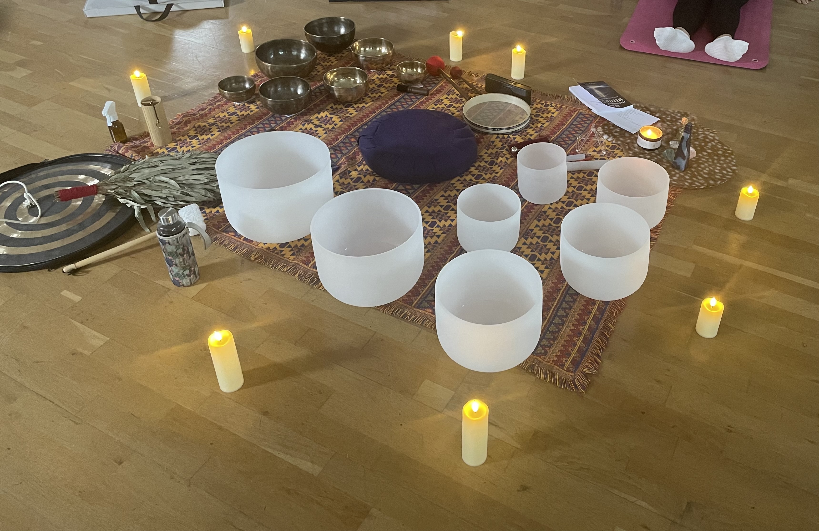 Crystal singing bowls arranged for a sound bath with gentle candlelight